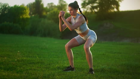 A-young-woman-jumps-a-burpee-exercise-in-a-Park-on-the-grass-at-sunset.-Slow-motion-fitness-training-of-a-young-woman-in-a-meadow